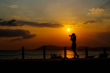 Girl with camera at sunset at sea