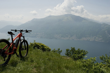 orange electric bicycle, e-bike, ebike, mountains, valley, lake of Como, sport, adventure, cloud, sun, alps, Lombardy, Italy