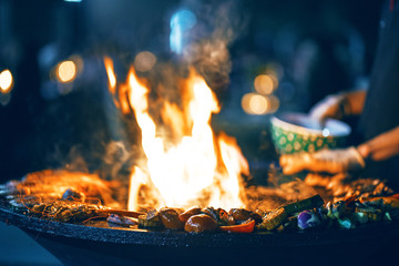 Preparation of shrimp, sea food and vegetables on the grill at night