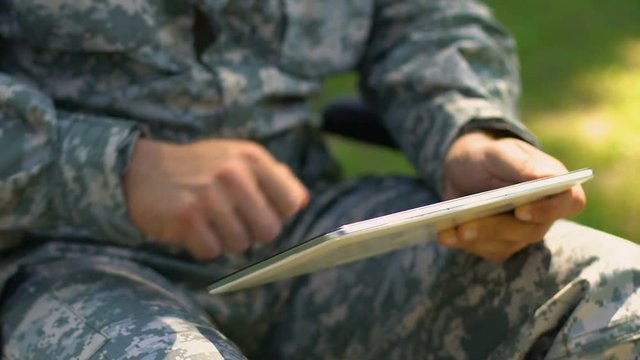 Soldier using tablet outdoors, online psychological support service for veterans