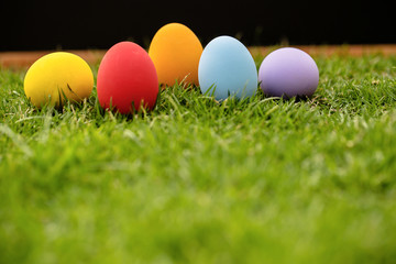 Colorful Easter eggs background. holiday, easter background. Colorful easter eggs on the green garden yard. symbol of easter's day festival. vivid color natural background. festive wallpaper.