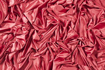 Red silk textured fabric with glitter folded folds with deep shadows