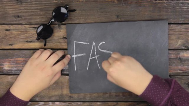 Top view. Man writes the word FASHION with chalk on a blackboard.
