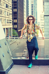 Young Man with brown curly hair, wearing sunglasses, patterned short sleeve shirt, baggy loose pants with suspenders, patterned sneakers, hanging old key as necklace, standing on balcony in New York..