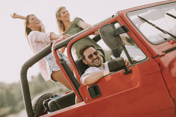 Group of young happy people enjoying road trip in red convertible