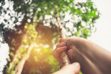 Closeup hand of person holding rope in forest nature concept is for idea or sport.