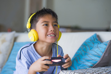 oung hispanic little kid excited and happy playing video game online with headphones holding...
