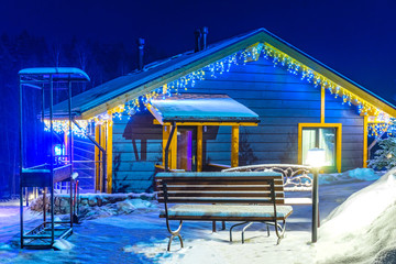 Holiday Christmas outside the city. The house is decorated for the Christmas holiday. Cottage covered with snow. Winter. The cottage is decorated with a light garland. Snow. The winter vacation.