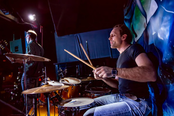 Drummer playing on drum set on stage.