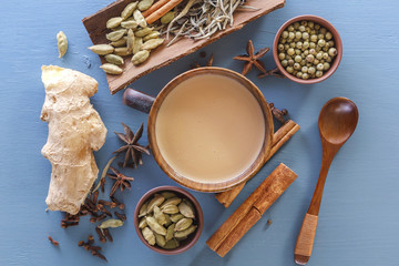 Hot Indian milk tea with spices - cinnamon, cardamom, ginger, cloves, tubby, sweet pepper on a wine background. View from above. Close-up