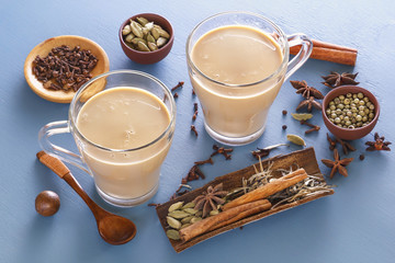 Hot Indian milk tea with spices - cinnamon, cardamom, ginger, cloves, tubby, sweet pepper on a wine background. Close-up