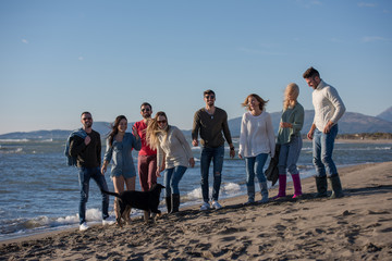 young friends jumping together at autumn beach