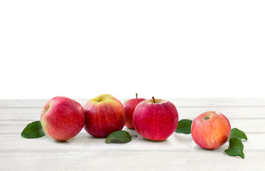 Ripe red juicy apples and leaves apple tree on white wooden table on a white background with space for text
