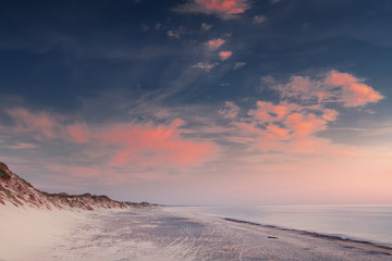 Seaside beach of Skagen with waves and dramatic storm clouds during sunset with a holiday house. Coast at the Top of Denmark in North Jutland in Denmark, Skagerrak, North Sea
