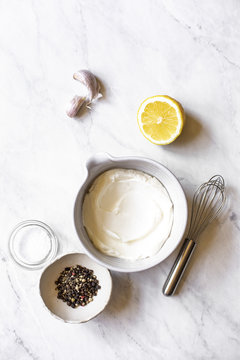 Ingredients for a salad dressing, yoghurt, lemon, peppers, garlic.