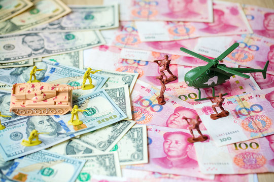 Toy set, tank, soldiers and helicopter placed on US banknotes,dollar currency pile and china banknotes, yuan currency. business and economy war. new world war from business and economy concept.