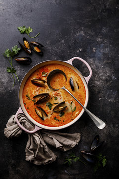 Seafood soup with prawns, mussels and tomato on dark background copy space
