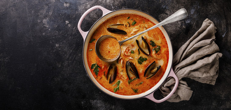 Seafood soup with prawns, mussels and tomato on dark background copy space