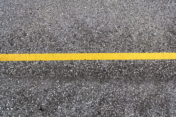 Fototapeta premium Top view of a tarmac road surface with yellow horizontal traffic line as background