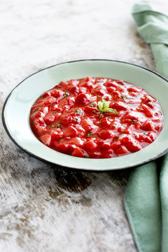 Strawberry Basil Jam served in a enamel bowl. Photographed on a rustic white background.