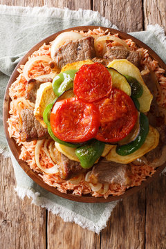 Middle Eastern Dish Maklouba or Makloubeh rice with meat and vegetables close-up on a plate. Vertical top view
