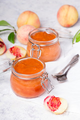 Homemade peach jam with organic fruit. Sweet preserves on a light background