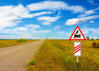 Railroad Level Crossing sign on the roadside of an empty road in the summer steppe of Khakassia. Train sign railroad ahead. © Вера Тихонова