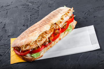 Sandwich from fresh pita bread with fillet grilled chicken, lettuce, slices of fresh tomatoes, pickles and cheese