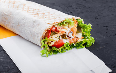 Burrito wraps from fillet grilled chicken, lettuce, slices of fresh tomatoes, pickles and cheese on...