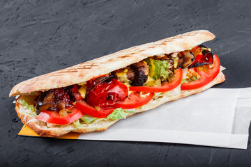 Vegetarian sandwich from grilled vegetables and fresh pita bread on dark wooden background. Shashlik or Shish kebab