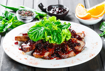 Fried beef meat with wild berries sauce on plate on wooden background. Hot meat dish. Top view