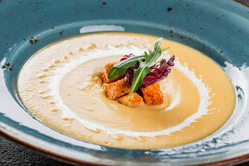 Cream soup of lentils with breadcrumbs on plate on dark grey stone background. Healthy vegan food