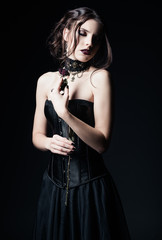 Naklejka premium Dramatic portrait of beautiful sad goth girl holding withered rose in hands