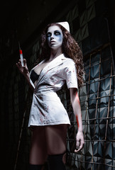 Horror shot: creepy wicked insane nurse (doctor) in bloody uniform, with syringe in hand. Zombie...