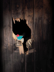 Zombie hand through hole cracked in rustic wood.Halloween theme
