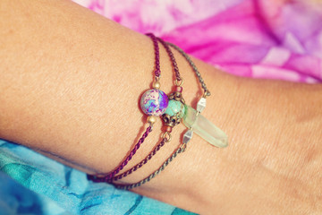 Female hand wearing natural stone bead bracelets on tiny waxed string