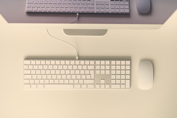 Minimalistic workspace. White office desk table with computer keyboard, mouse, monitor. Top view, copy space, flat lay.