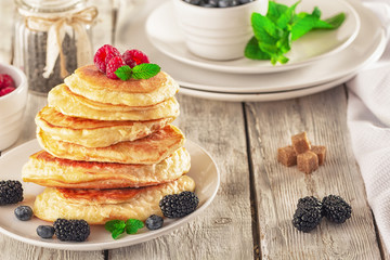 Pancakes with blueberries, honey and raspberry on a wooden background