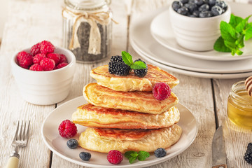 Pancakes with blueberries, honey and raspberry on a wooden background