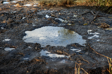 Fototapeta premium Spills of crude oil on the soil surface. Crater of the volcano.Mud volcano