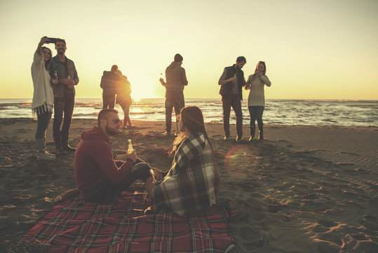 Couple enjoying with friends at sunset on the beach
