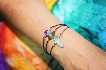 Female hand wearing natural stone bead bracelets on tiny waxed string