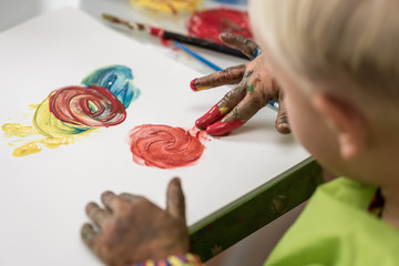 Little boy having fun painting with fingers