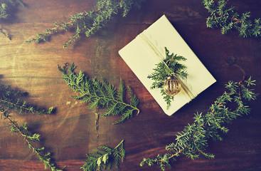 Naklejka premium Christmas present with natural evergreen twigs on wooden background. Flatlay. Copy space