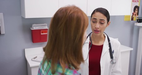 Professional latina doctor attending middle aged patient indoors medical clinic