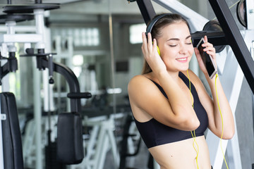 Fototapeta premium Woman Listening Music, Doing Workout Exercises.Relaxing After Fitness Training in gym.She smile and happy.