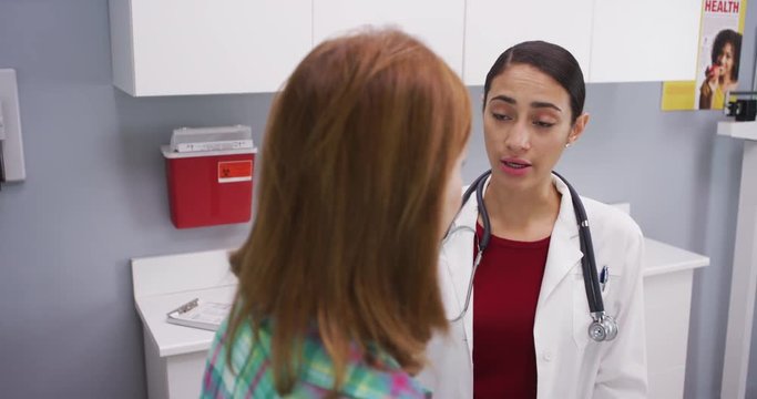 Professional latina doctor attending middle aged patient indoors medical clinic