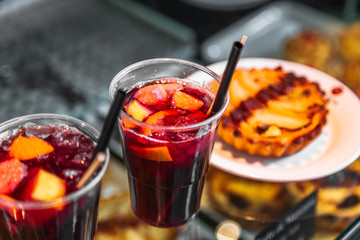 Refreshing sangria or compote with fruits stands near cakes
