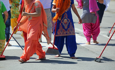 sikh women during a religion ceremony on the street with brooms