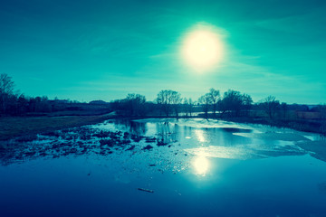 Fototapeta premium View of a river with floating ice in the evening in early spring. Rural landscape. 